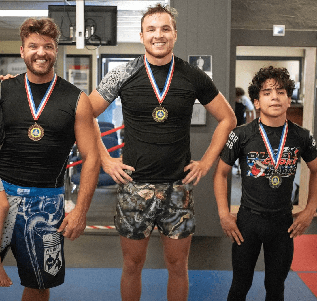 Three competitors wearing medals after a grappling event