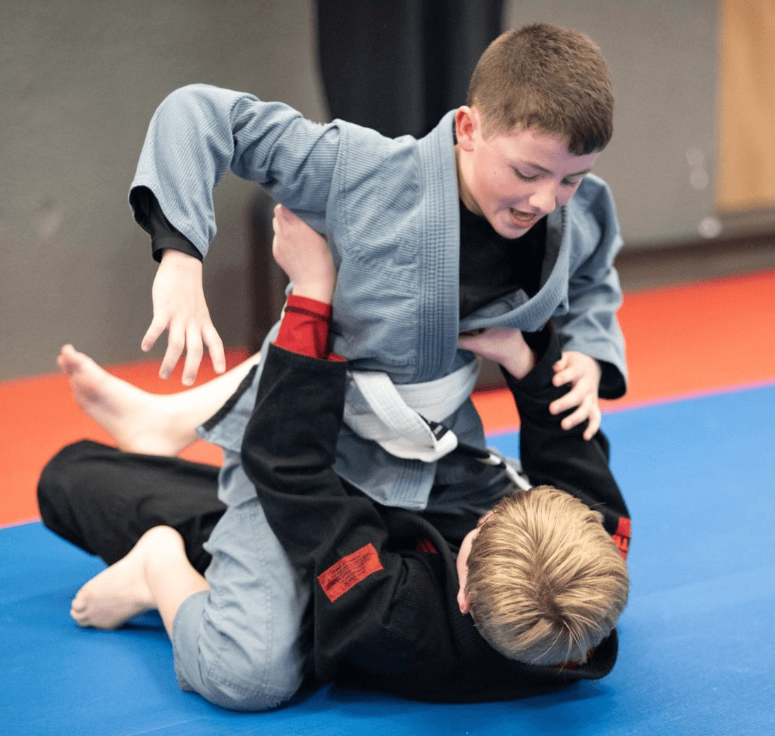 Young grappling partners practicing a position in gis